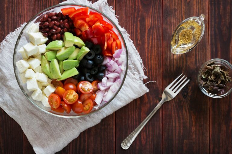 A colorful Mediterranean-style meal with vegetables, beans, whole grains, fish, nuts, and olive oil on a kitchen table.