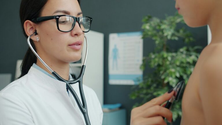 Adult patient and doctor reviewing blood pressure readings, lab results, and family history at a desk.