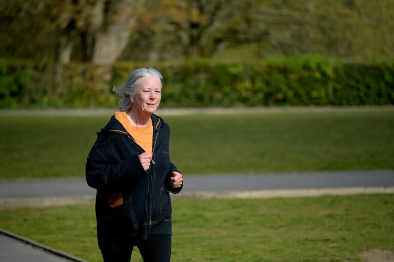 Adults briskly walking outdoors while another person performs resistance exercises with bands.